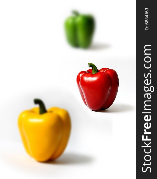 Three peppers in different colors on white background