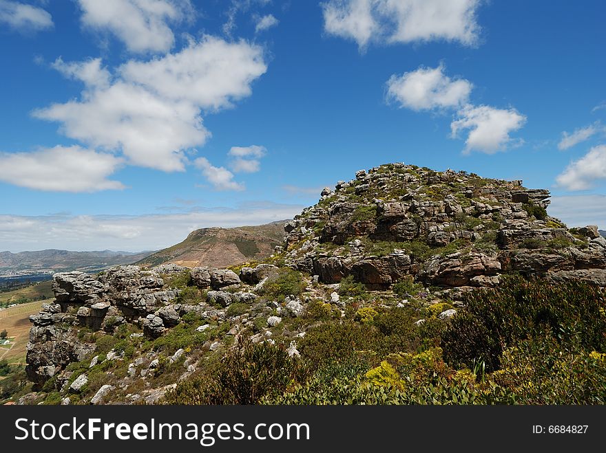 This small mountain peak is called the Eagle's Nest and is found in Cape Town, South Africa.