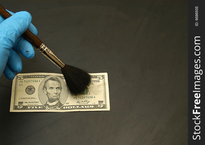 Thumb print developed on a $ 5.00 bill using standard black fingerprint powder.