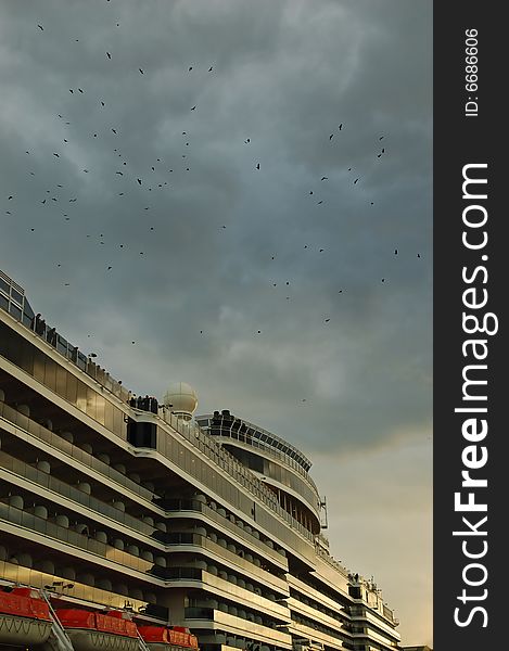 Cruise ship docked in port with birds on dramatic sky. Cruise ship docked in port with birds on dramatic sky