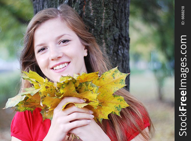 Young happy beautiful woman in red with yellow maple leaves. Young happy beautiful woman in red with yellow maple leaves
