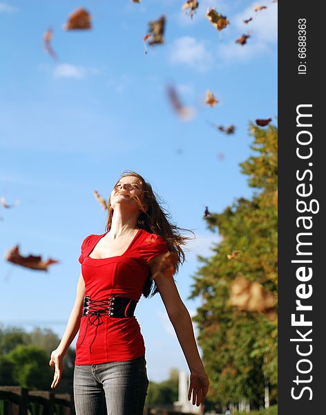 Young happy woman in red throw the maple leaf. Young happy woman in red throw the maple leaf