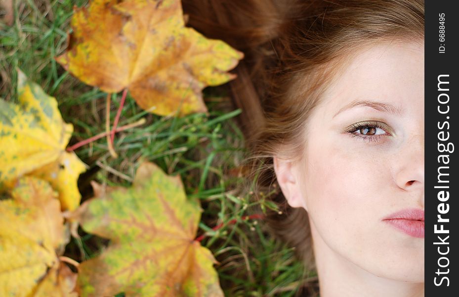 Young beautiful woman with maple leaf around her face