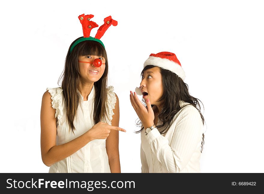 Teenager Asian girls in antlers head wear and red nose, and Santa Claus hat, having a conversation and sharing tales at a Christmas party. Teenager Asian girls in antlers head wear and red nose, and Santa Claus hat, having a conversation and sharing tales at a Christmas party.