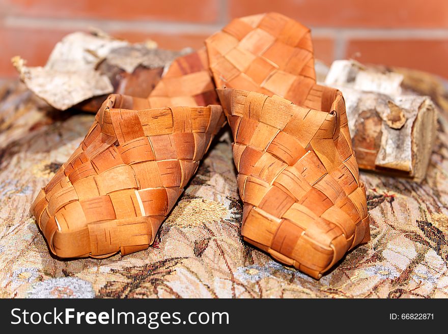 Pair of Russian bast shoes on birch log indoors