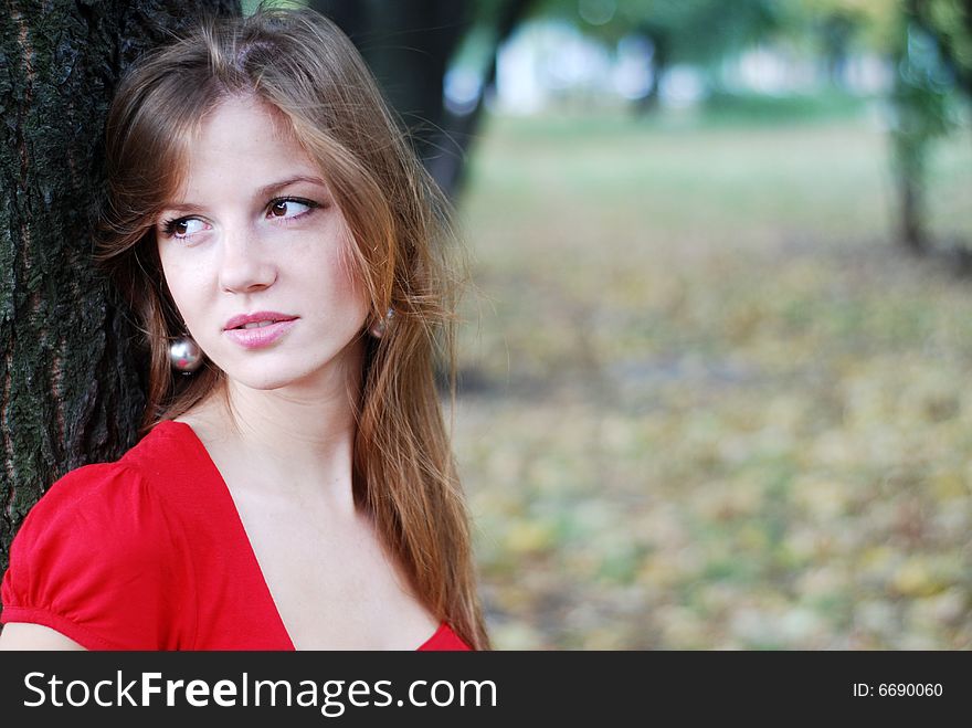 Young beautiful woman in red near the tree. Young beautiful woman in red near the tree