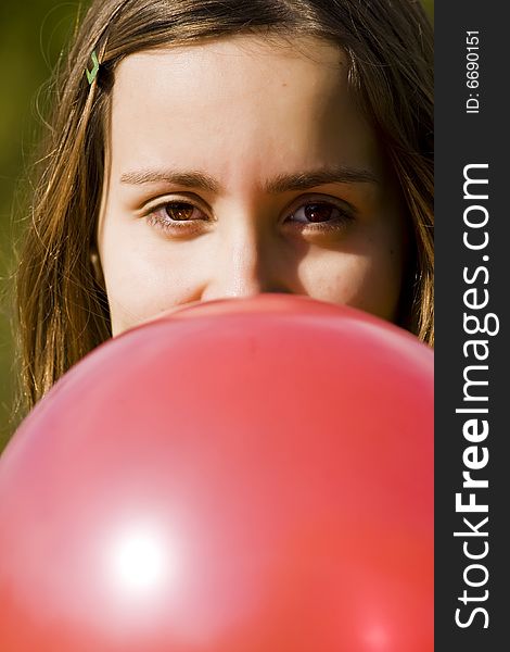 Young woman inflating red balloon, vertical composition