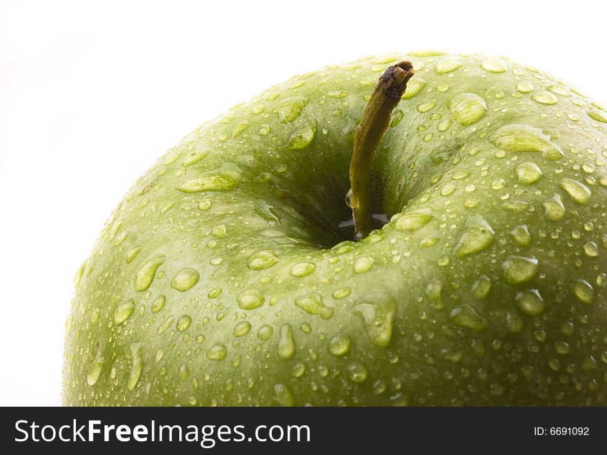 Macro closeup of a green apple with water droplets against a white background. Macro closeup of a green apple with water droplets against a white background