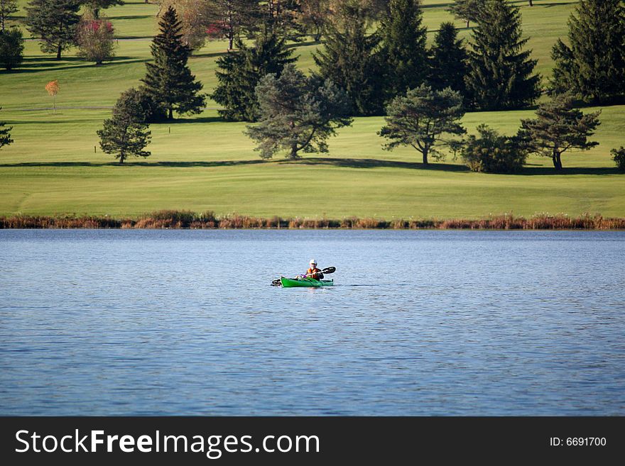 Single kayaker in a lake near golfcourse. Single kayaker in a lake near golfcourse