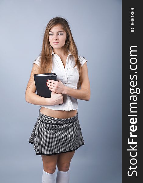 Young woman with textbooks on grey background