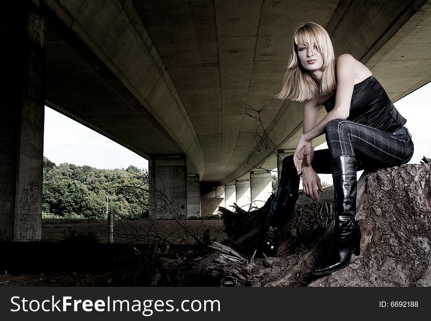 Fashion shoot of a beautiful girl posing under a bridge