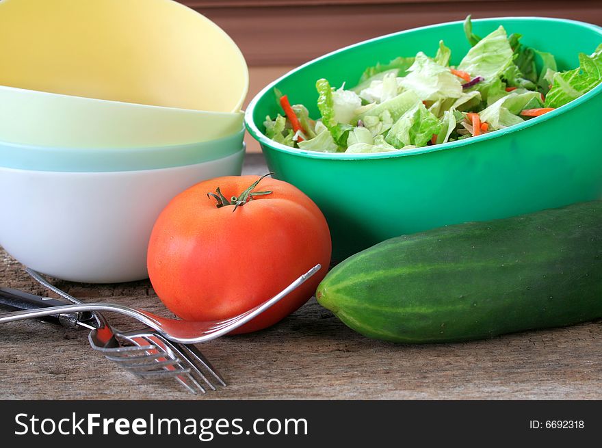 The fixings for a tossed salad with forks and bowls ready to be used.