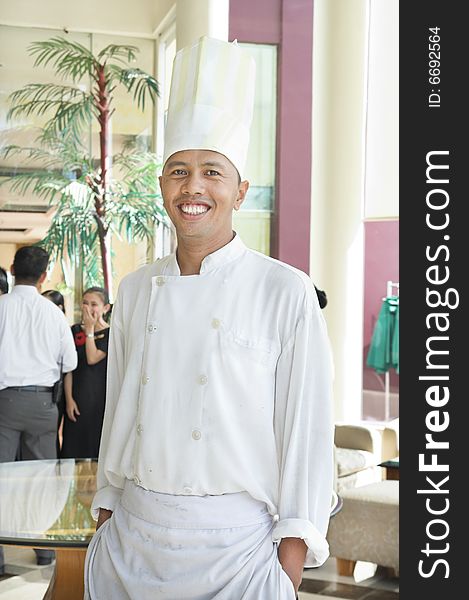 Chef standing and smiling, waitress at background