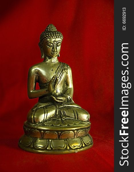 Shakyamuni Buddha figure with red fabric background - shallow depth of field