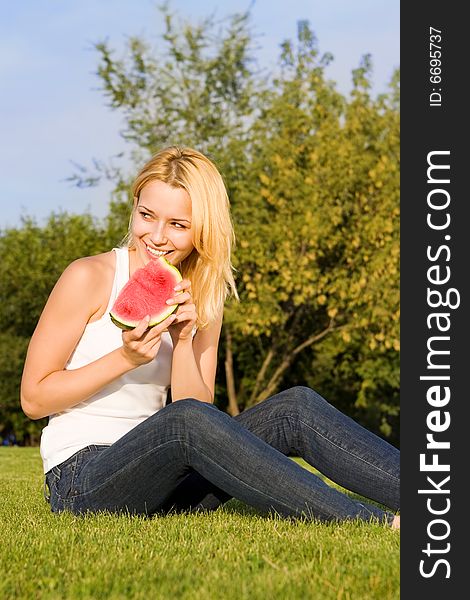 Young blonde eats watermelon in the park