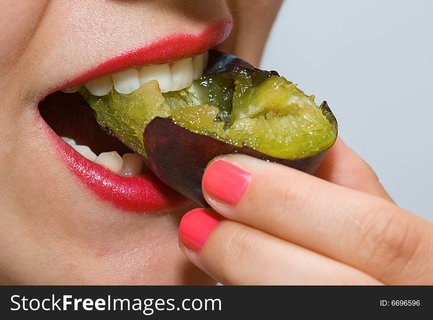Attractive girl with red lipstick, eating a plum. Attractive girl with red lipstick, eating a plum