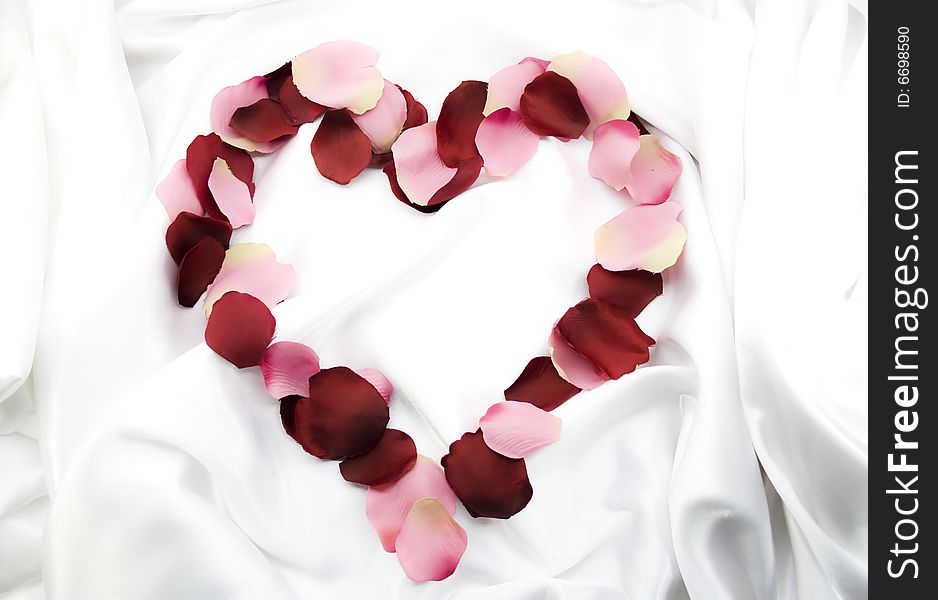 Symbol of heart from rose-petals on white silk