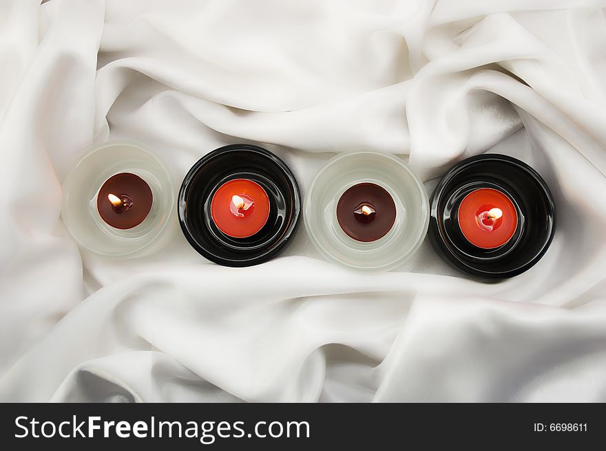 Candles in candlesticks on white silk