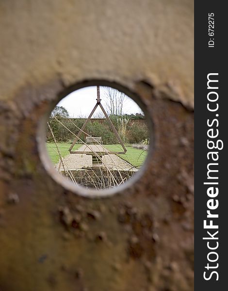 A view through a metal hole looking into garden. A view through a metal hole looking into garden.