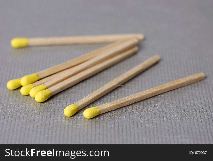 Yellow tipped matches scattered on a metallic surface