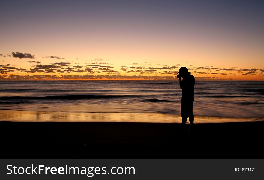 Silhouette of a photographer taking a picture of the sunrise on the beach. Silhouette of a photographer taking a picture of the sunrise on the beach