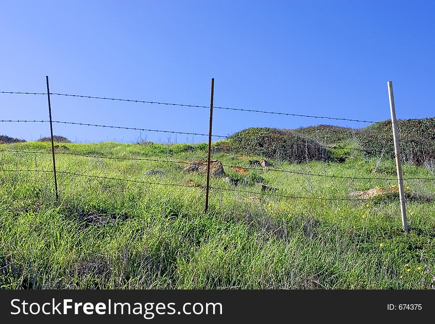 Old fence and green fields with deep blue sky