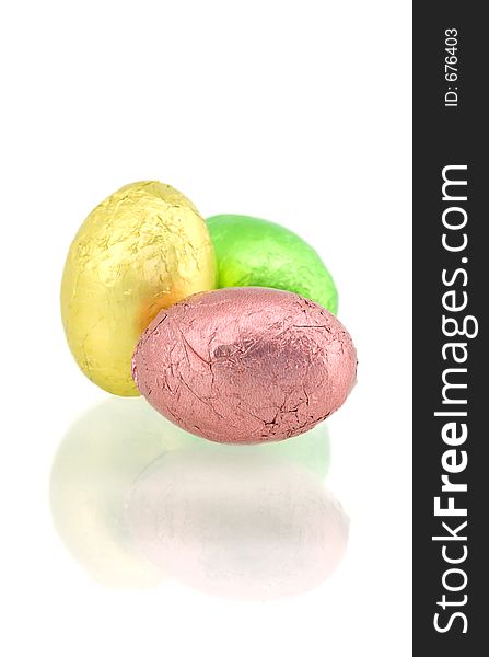 Colorful foil wrapped chocolate eggs on white background - with reflection. Colorful foil wrapped chocolate eggs on white background - with reflection