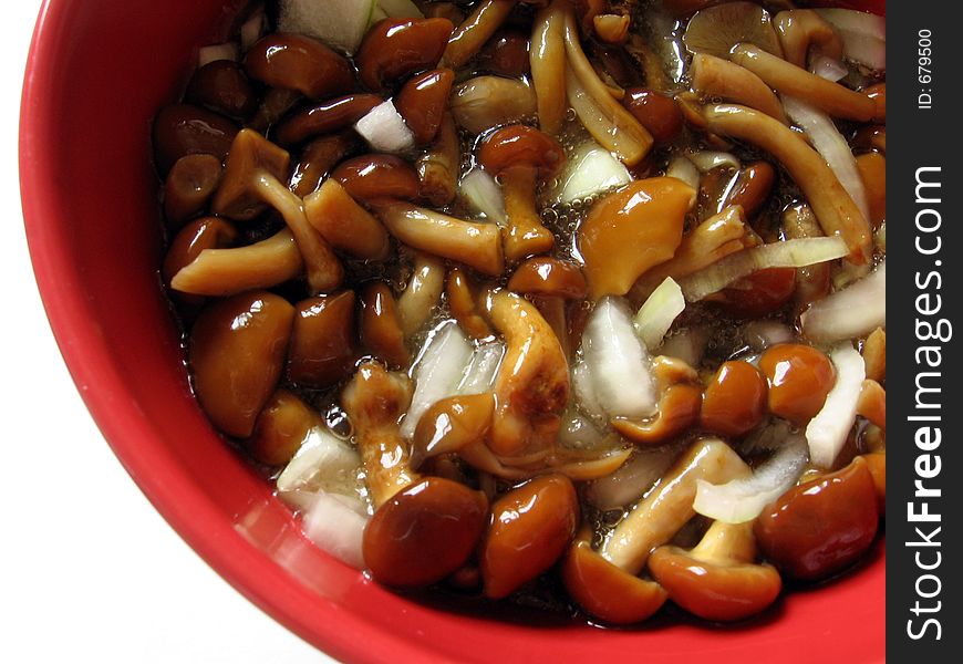 Marinaded mushrooms with onion and oil in the red bowl.