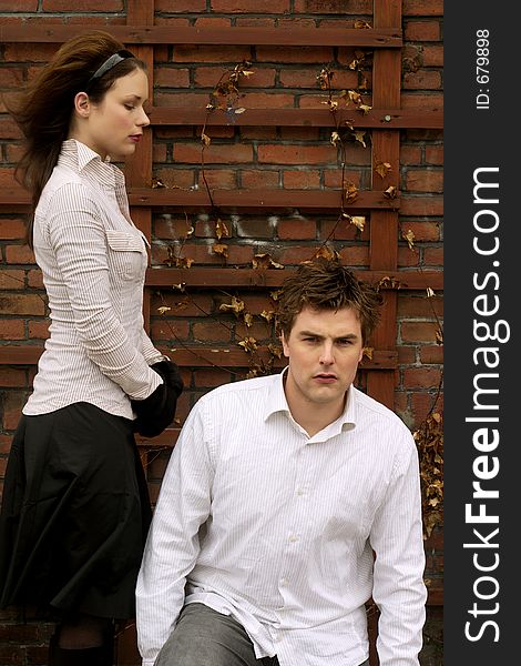 A Couple in white posing in front of brick wall. A Couple in white posing in front of brick wall