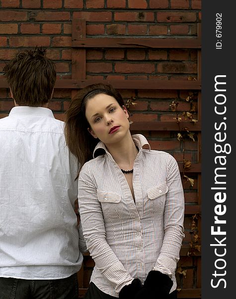 A Couple in white posing in front of brick wall. A Couple in white posing in front of brick wall