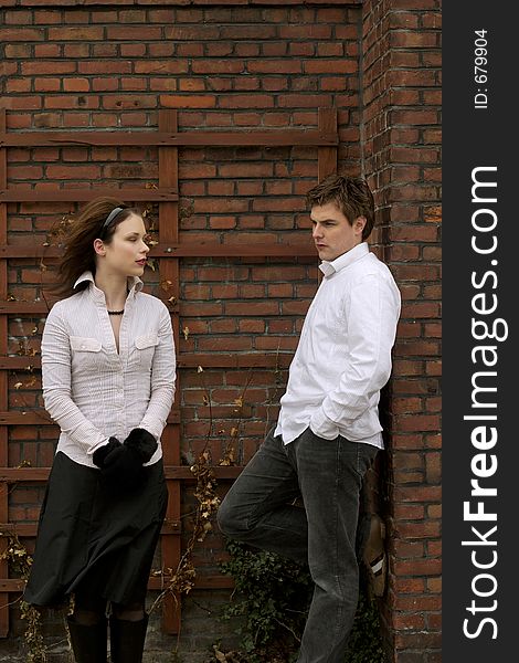 A Couple in white posing in front of brick wall. A Couple in white posing in front of brick wall