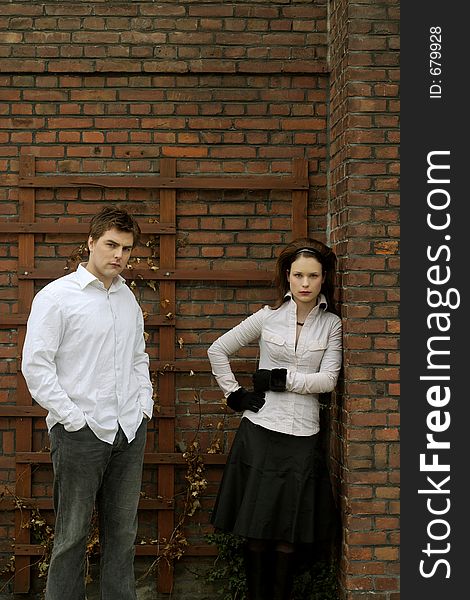 A couple posing in front of a brick wall. A couple posing in front of a brick wall
