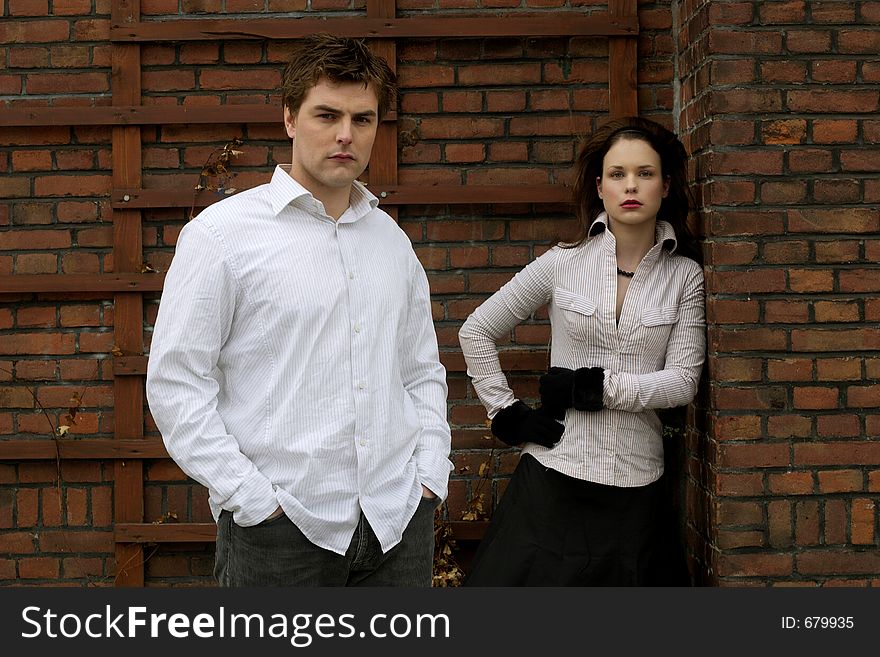 A couple posing in front of a brick wall. A couple posing in front of a brick wall