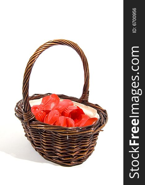 Wicker basket filled with red rose peddles on a white background