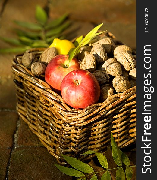 Apples and lemon with lot of walnuts in a basket. Apples and lemon with lot of walnuts in a basket
