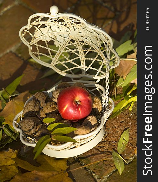 Apple with lot of walnuts in a white basket. Apple with lot of walnuts in a white basket