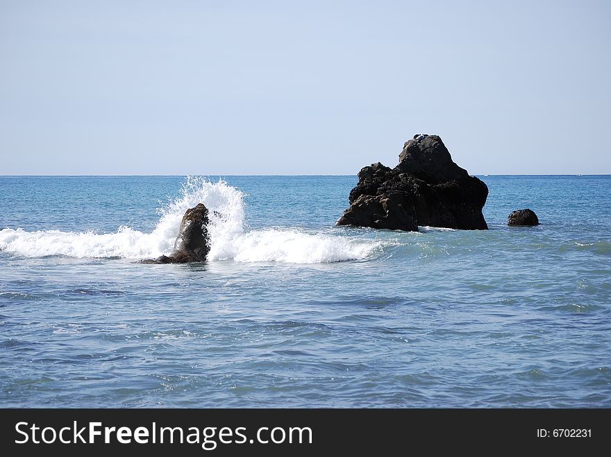 Rocks in the ocean with waves crashing