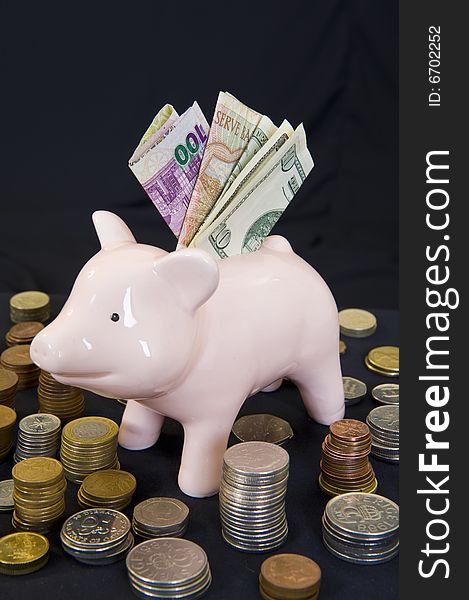 Piggy bank with various international currencies on a black background. Piggy bank with various international currencies on a black background.