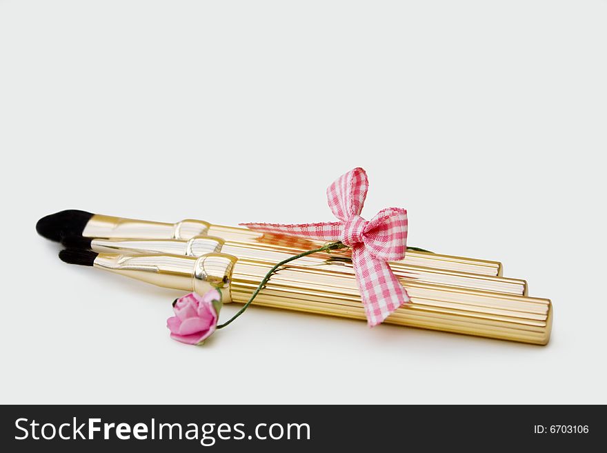 Set of golden makeup brushes with a flower decoration. Clipping path included for easy removal. Set of golden makeup brushes with a flower decoration. Clipping path included for easy removal.