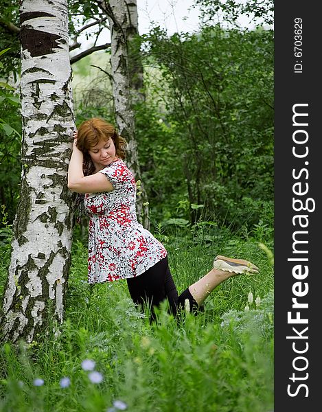 The brown-haired woman leans against a birch. The brown-haired woman leans against a birch
