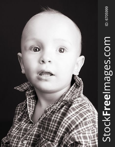 Serious blond toddler against a black background