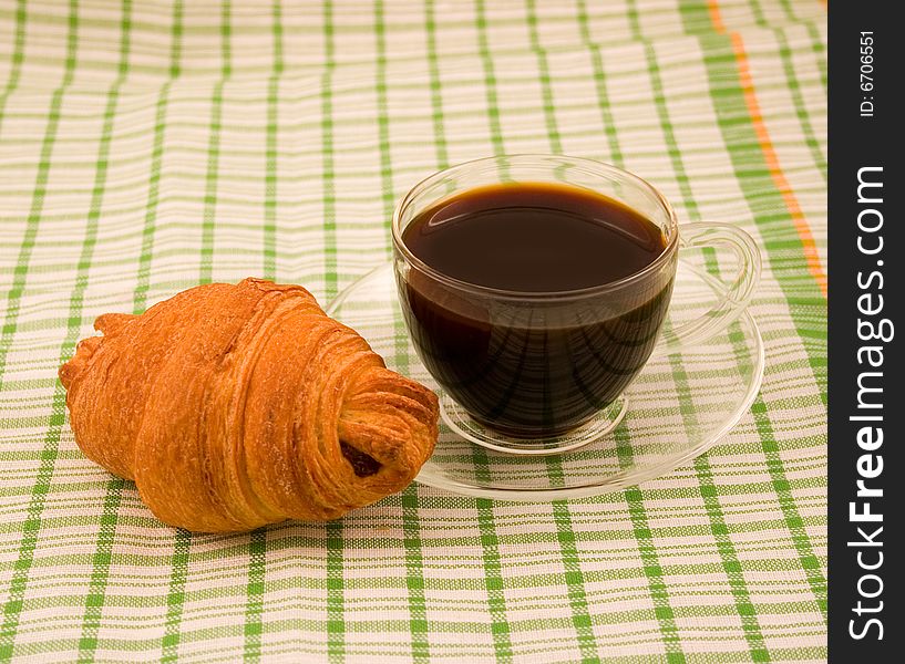 Roll tasty fresh from puff test with cup black morning coffee on green striped napkin