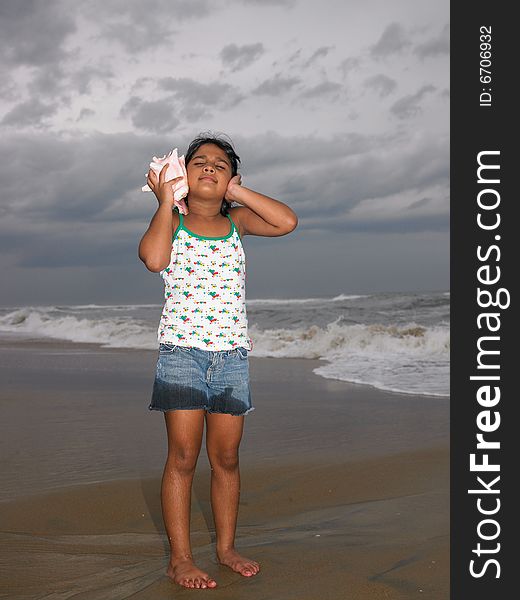 Asian girl listening to the conch in the beach