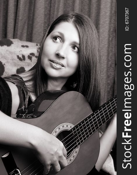 Mature brunette, playing guitar in her house. Mature brunette, playing guitar in her house