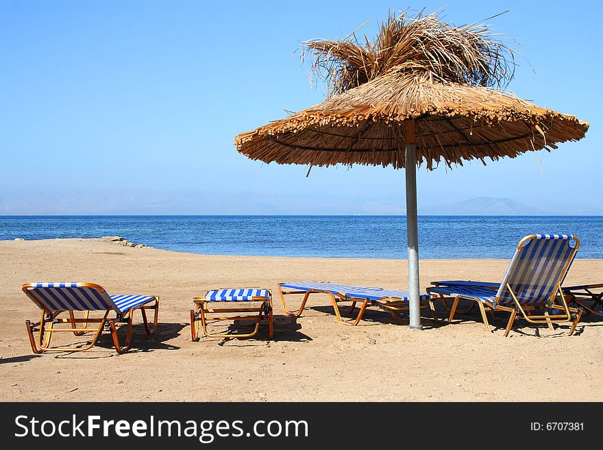 Beach and sea. Sunshade with chairs on sand. Beach and sea. Sunshade with chairs on sand