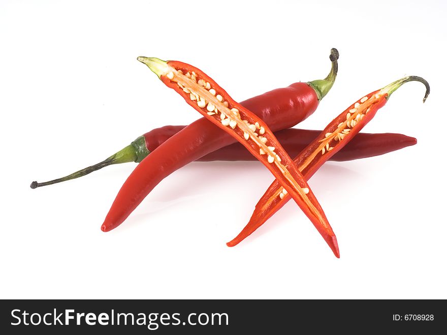 Three red chili peppers on a white background, two unimpaired and one cut open. Three red chili peppers on a white background, two unimpaired and one cut open.