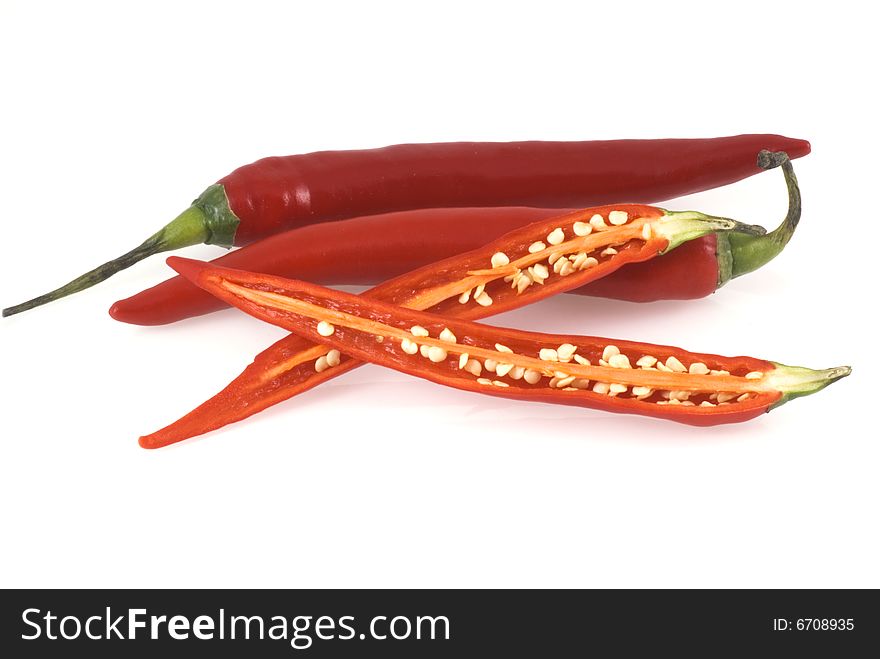 Three red chili peppers on a white background, two unimpaired and one cut open. Three red chili peppers on a white background, two unimpaired and one cut open.