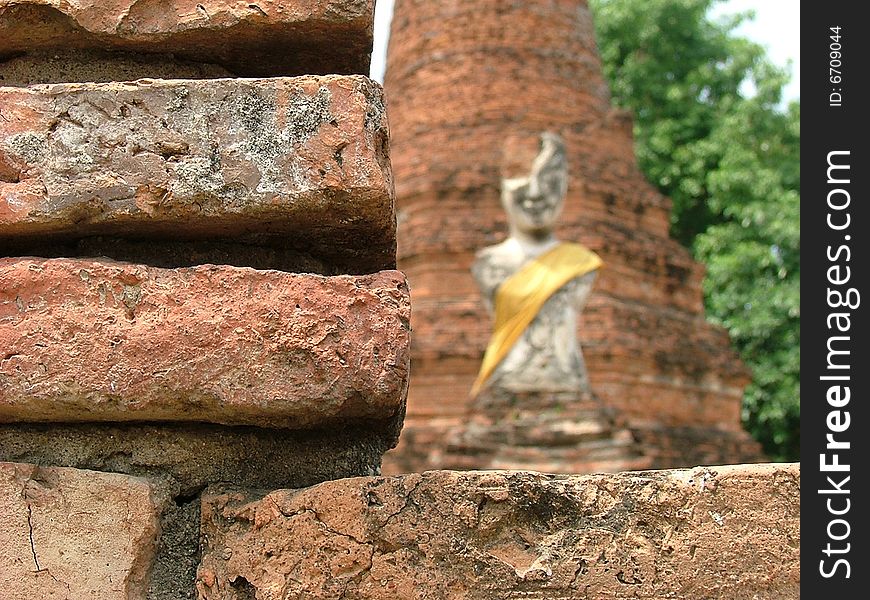 The old and ancient buddha image infront of broken pagoda in Ayuthaya, Thailand. The old and ancient buddha image infront of broken pagoda in Ayuthaya, Thailand