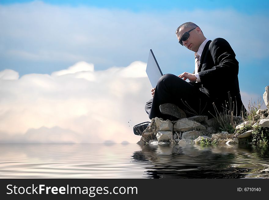 Men with his laptop working on a stone wall above water level