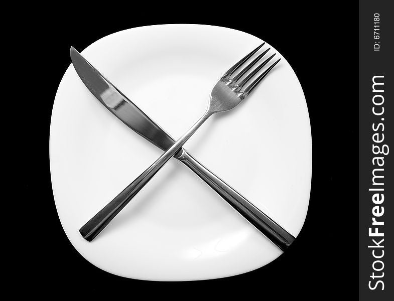 Fork and knife on plate. Black background.